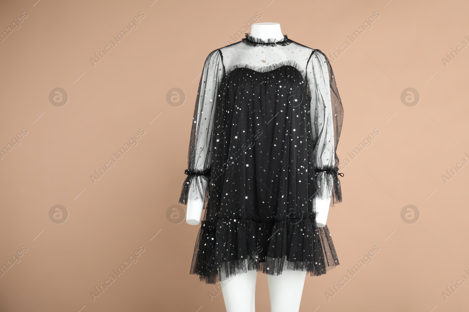 Photo of Female mannequin with stylish dress on light brown background, space for text