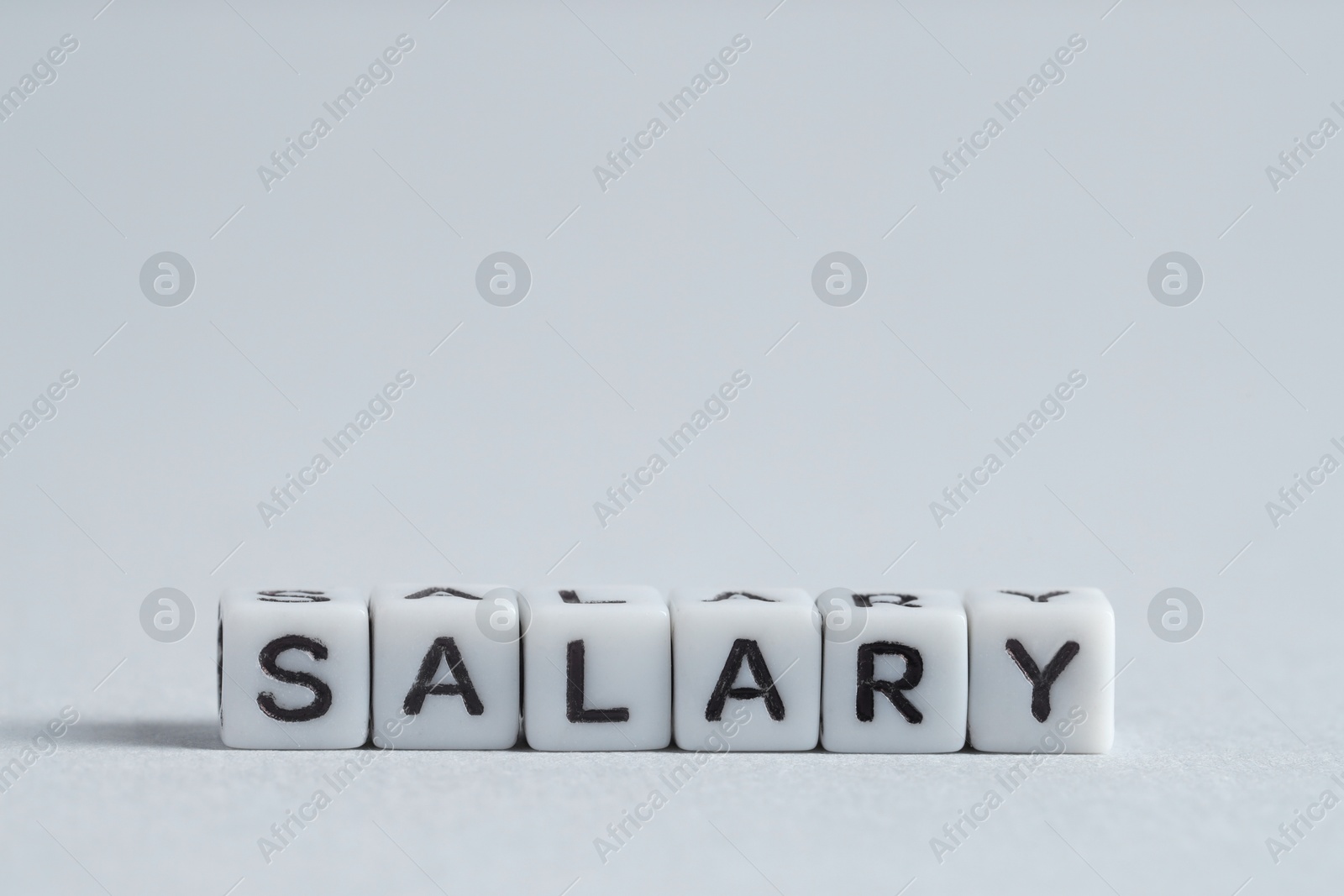 Photo of Word Salary made of cubes on light grey background, space for text