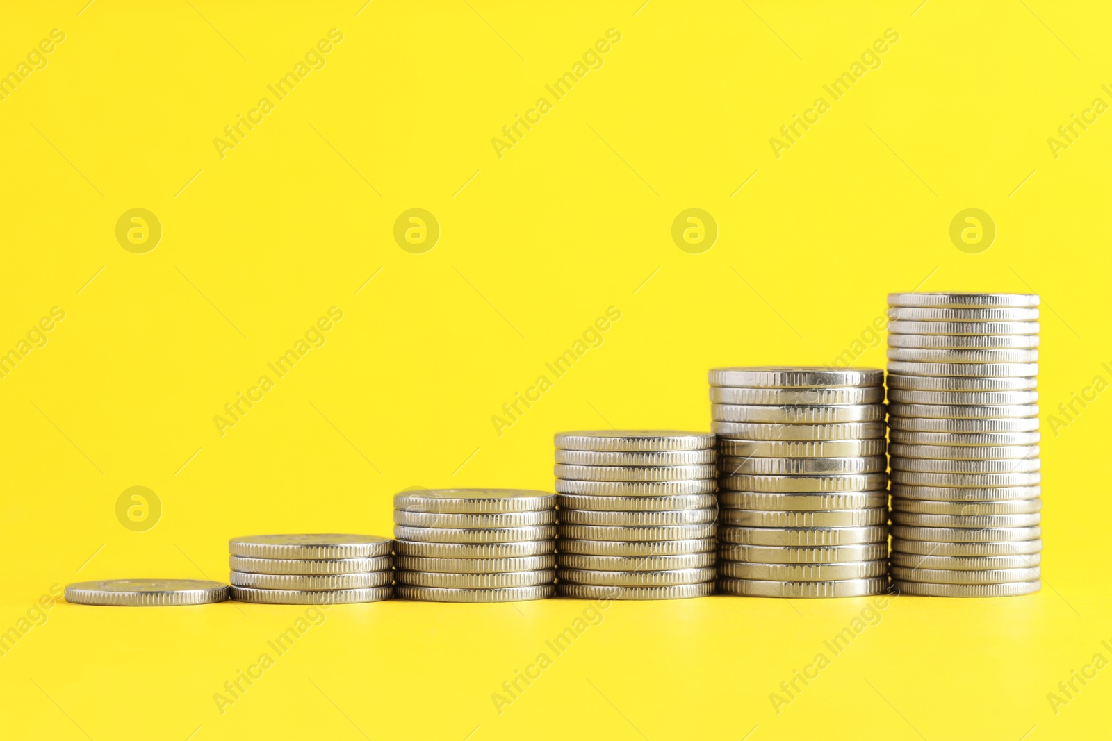 Photo of Salary concept. Stacked coins on yellow background, space for text