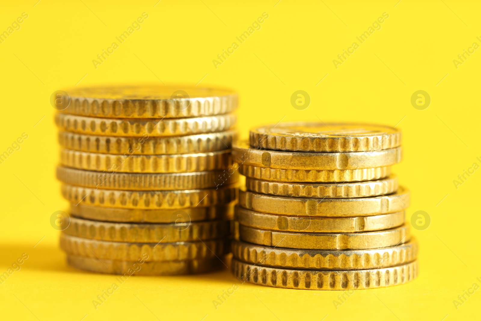 Photo of Salary concept. Stacked coins on yellow background, closeup