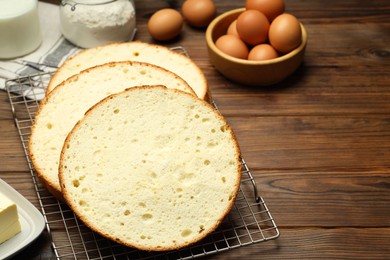 Tasty cut sponge cake and ingredients on wooden table