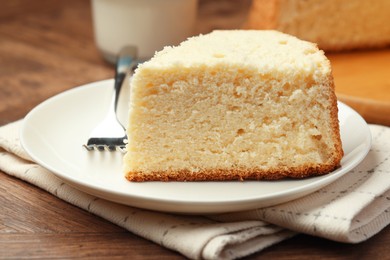 Photo of Piece of delicious sponge cake and fork on wooden table, closeup