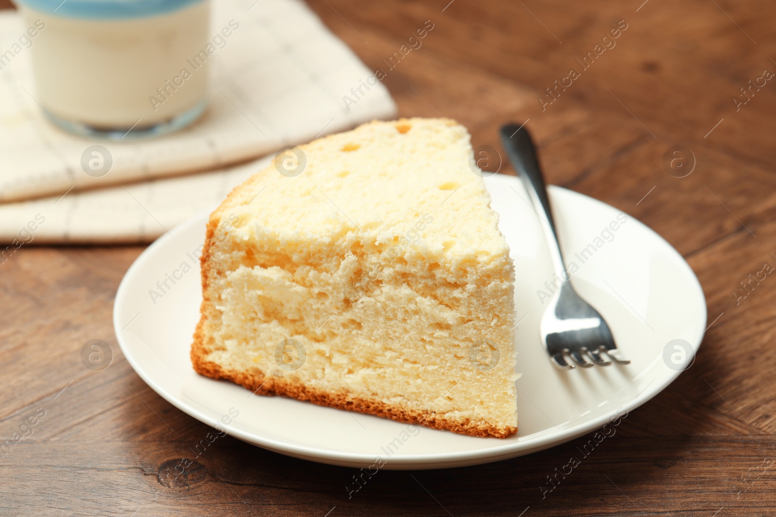 Photo of Piece of delicious sponge cake and fork on wooden table, closeup