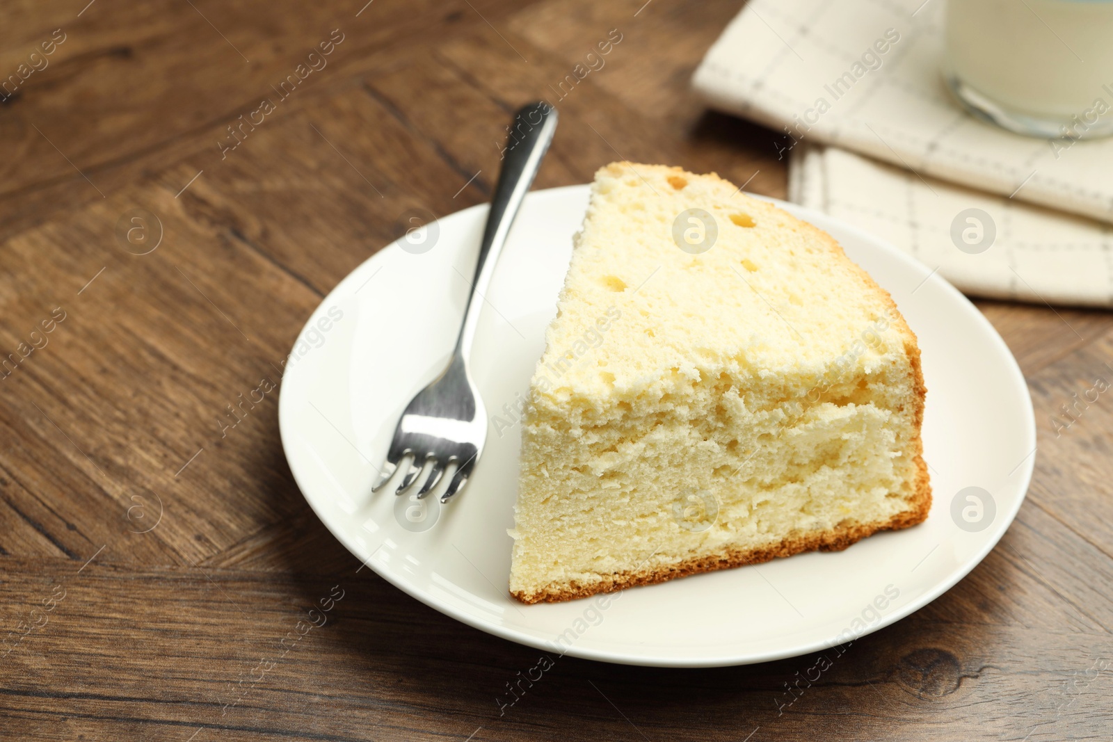 Photo of Piece of delicious sponge cake and fork on wooden table, closeup