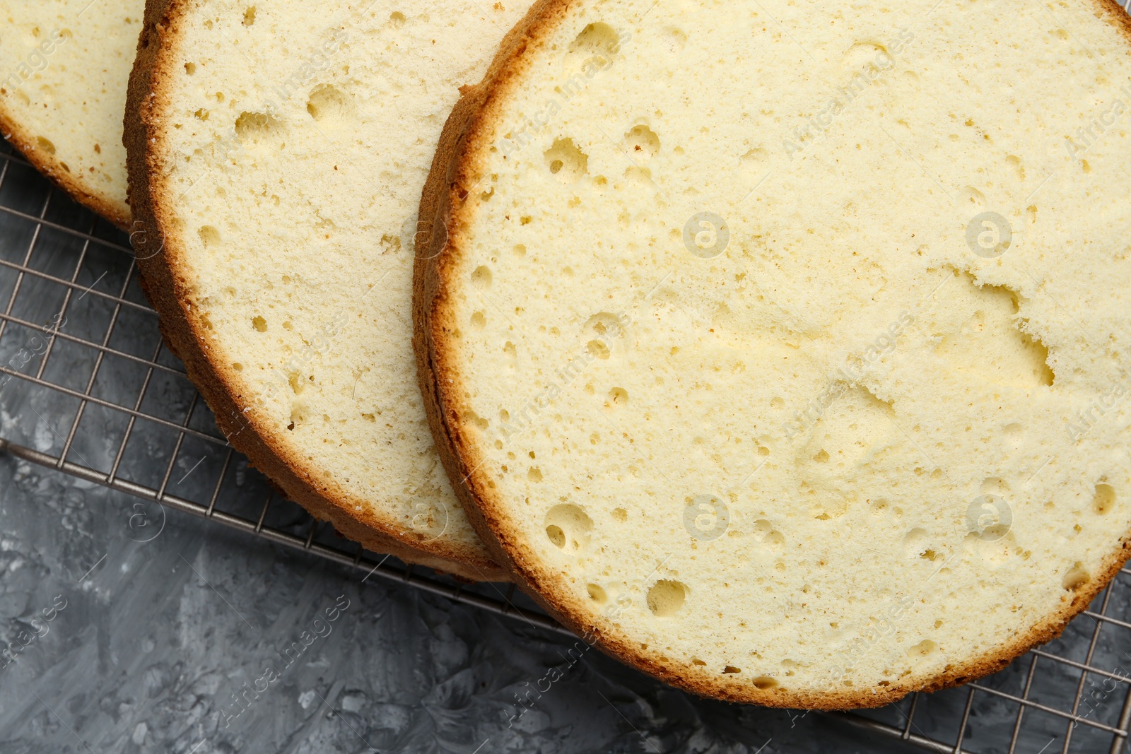 Photo of Delicious cut sponge cake on grey textured table, flat lay