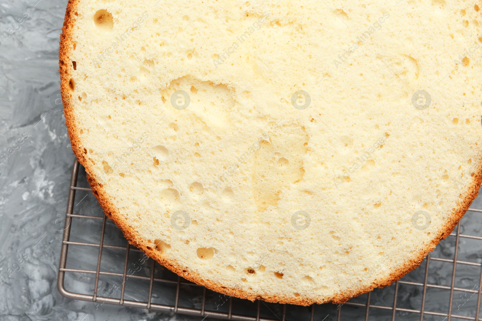 Photo of Delicious cut sponge cake on grey textured table, top view