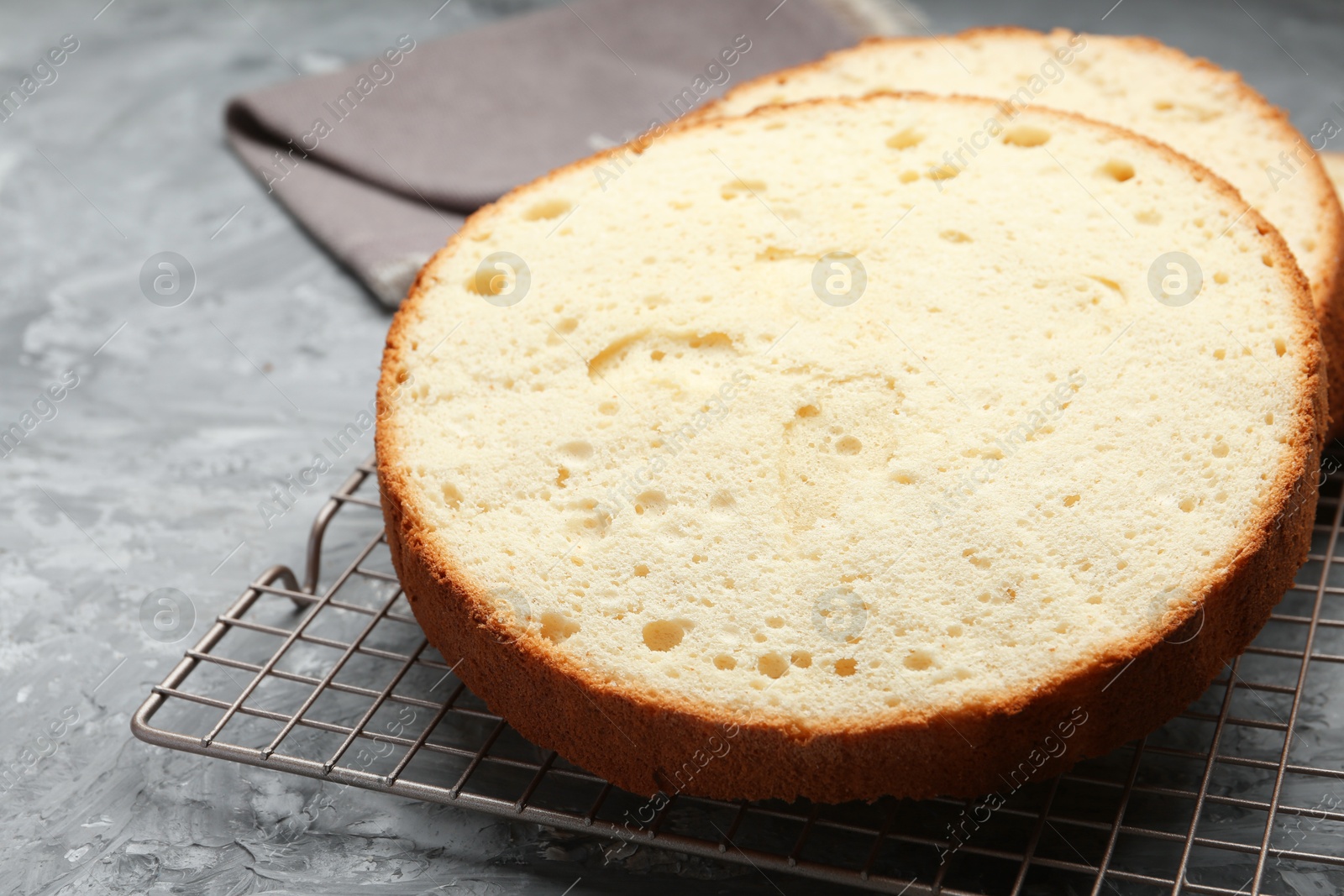 Photo of Delicious cut sponge cake on grey textured table, closeup