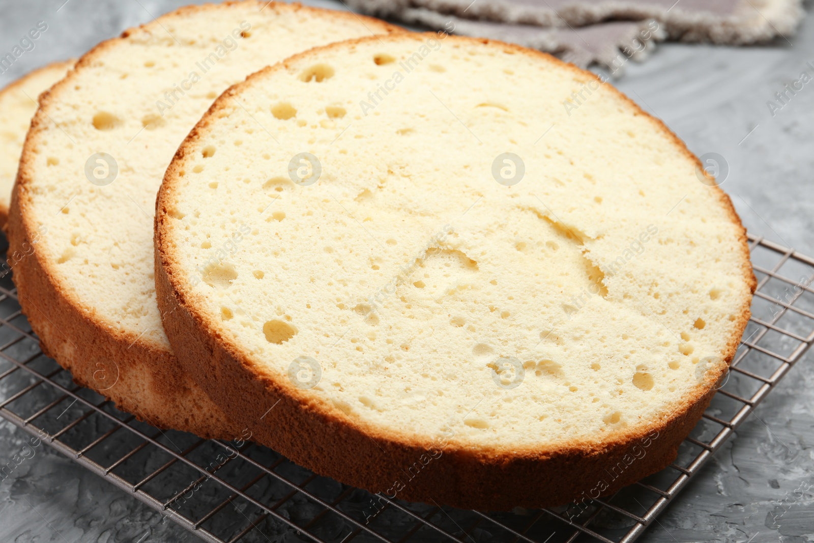 Photo of Delicious cut sponge cake on grey textured table, closeup