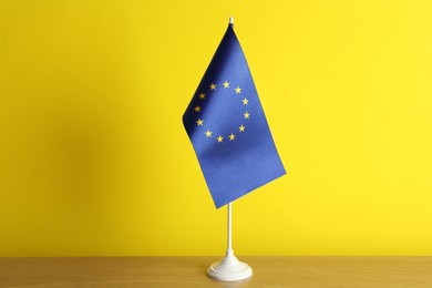 Photo of Flag of European Union on wooden table against yellow background