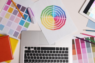 Photo of Designer's workplace with laptop, different palettes and stationery on white table, flat lay