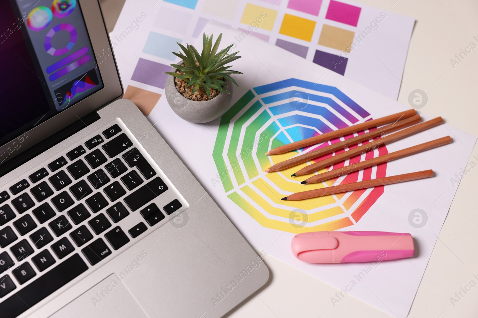 Photo of Designer's workplace with laptop, stationery and palettes on white table, above view