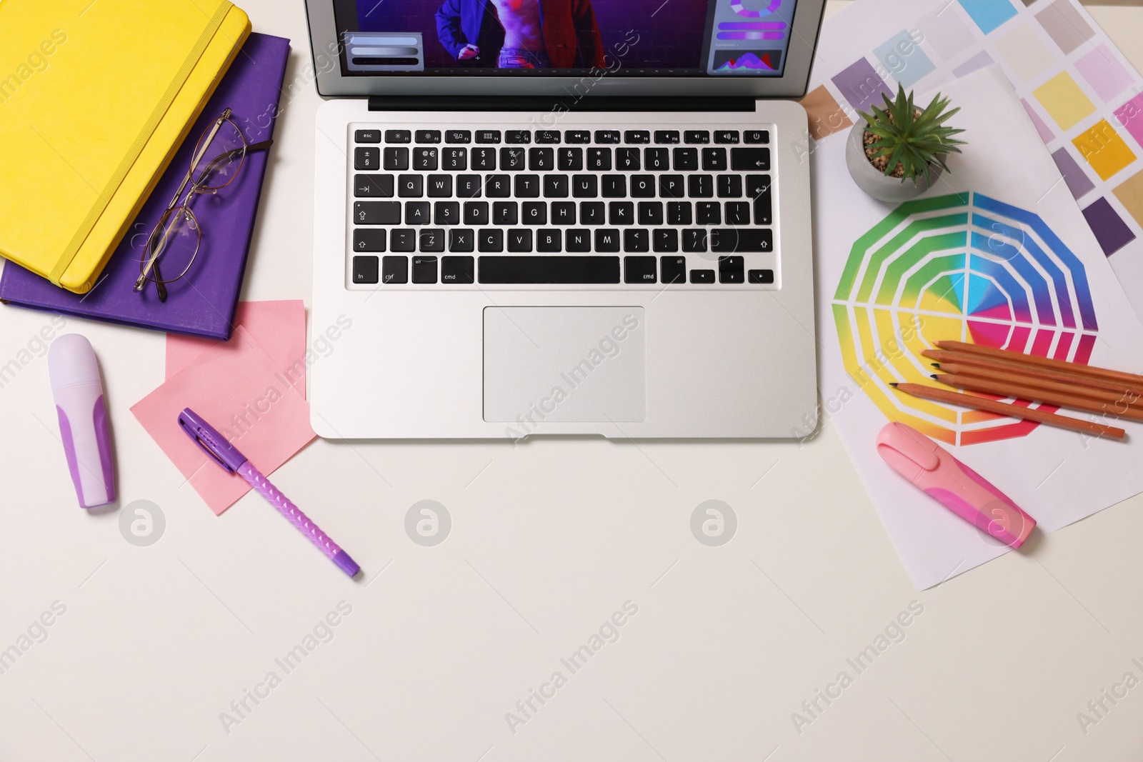 Photo of Designer's workplace with laptop, stationery and palettes on white table, flat lay. Space for text