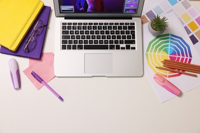 Photo of Designer's workplace with laptop, stationery and palettes on white table, flat lay. Space for text