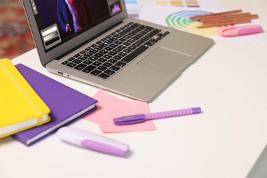 Photo of Designer's workplace with laptop and stationery on white table