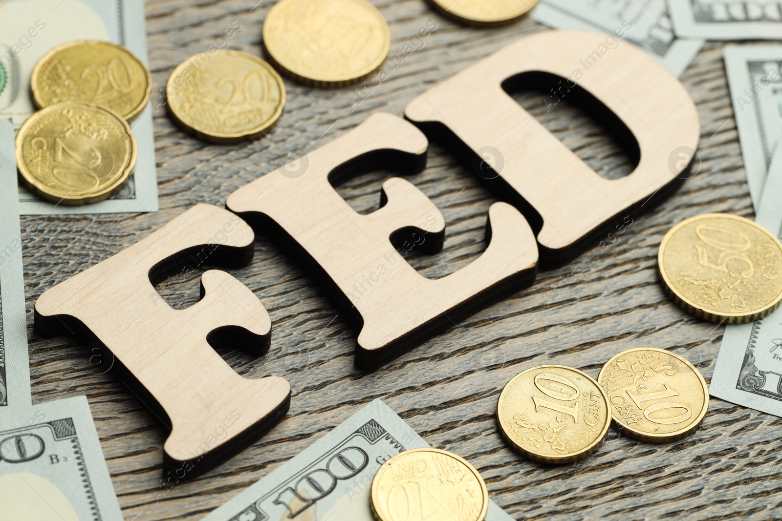 Photo of Word Fed (Federal Reserve System) made with letters, dollar banknotes and coins on wooden table, closeup