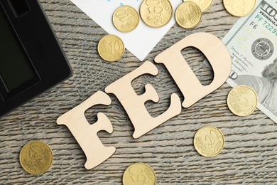 Photo of Word Fed (Federal Reserve System) made with letters, calculator, dollar banknote and coins on wooden table, flat lay