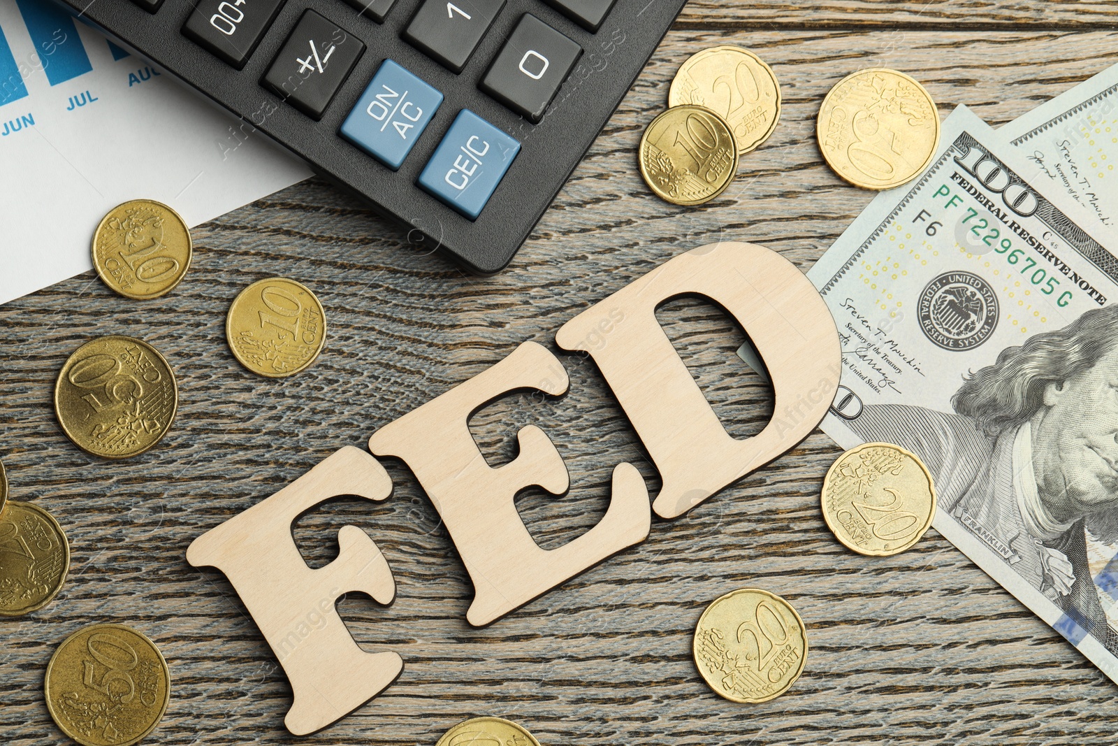 Photo of Word Fed (Federal Reserve System) made with letters, calculator, dollar banknotes and coins on wooden table, flat lay