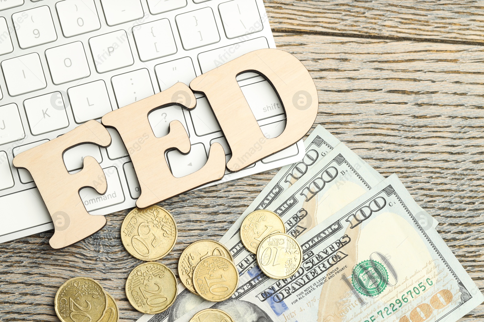 Photo of Word Fed (Federal Reserve System) made with letters, keyboard, dollar banknotes and coins on wooden table, flat lay