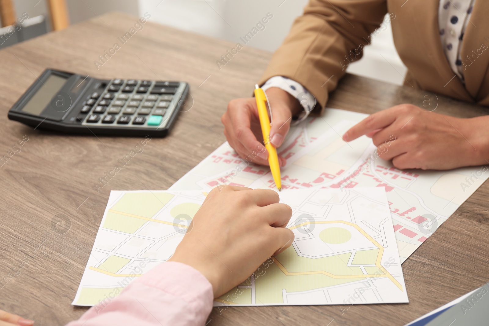 Photo of Real estate agent working with client at wooden table, closeup