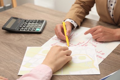 Photo of Real estate agent working with client at wooden table, closeup