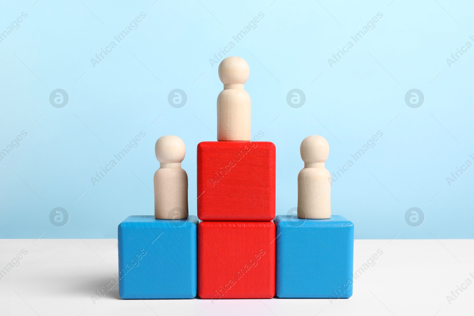 Photo of Winner. Wooden figures on podium against color background