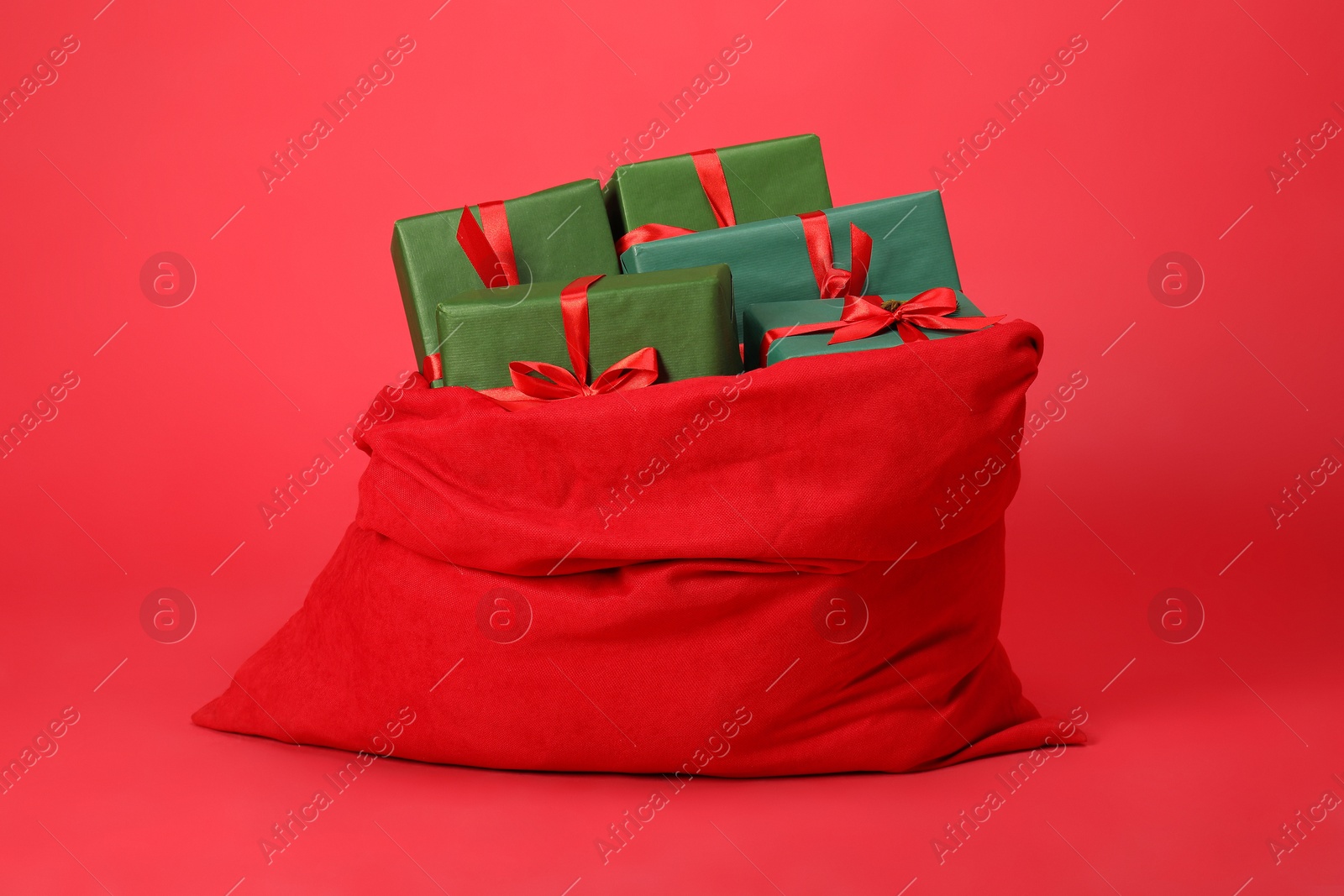 Photo of Santa Claus bag with gift boxes on red background