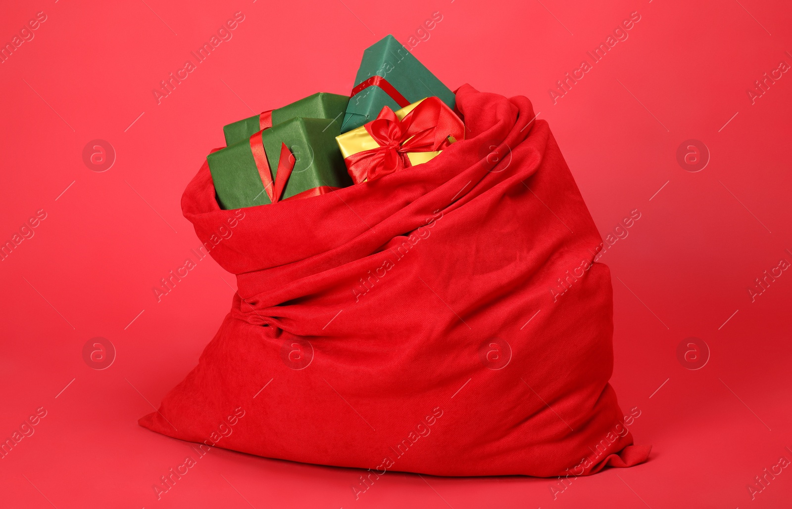 Photo of Santa Claus bag with gift boxes on red background