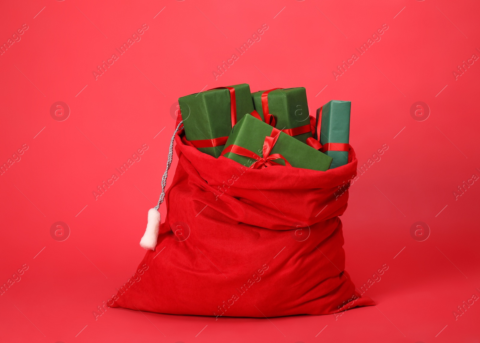 Photo of Santa Claus bag with gift boxes on red background