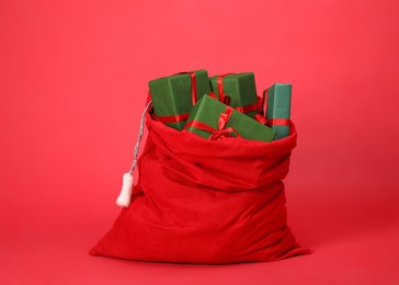 Photo of Santa Claus bag with gift boxes on red background