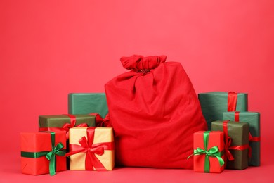 Photo of Santa Claus bag with gift boxes on red background