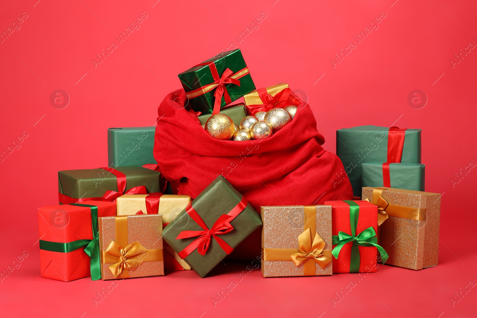 Photo of Santa Claus bag with baubles and gift boxes on red background