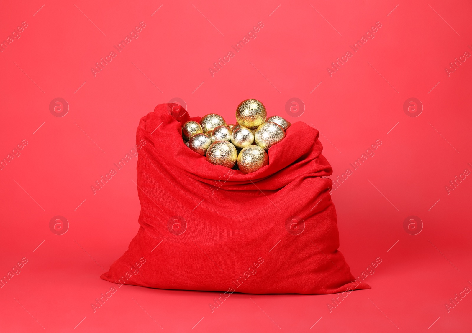 Photo of Santa Claus bag with baubles on red background