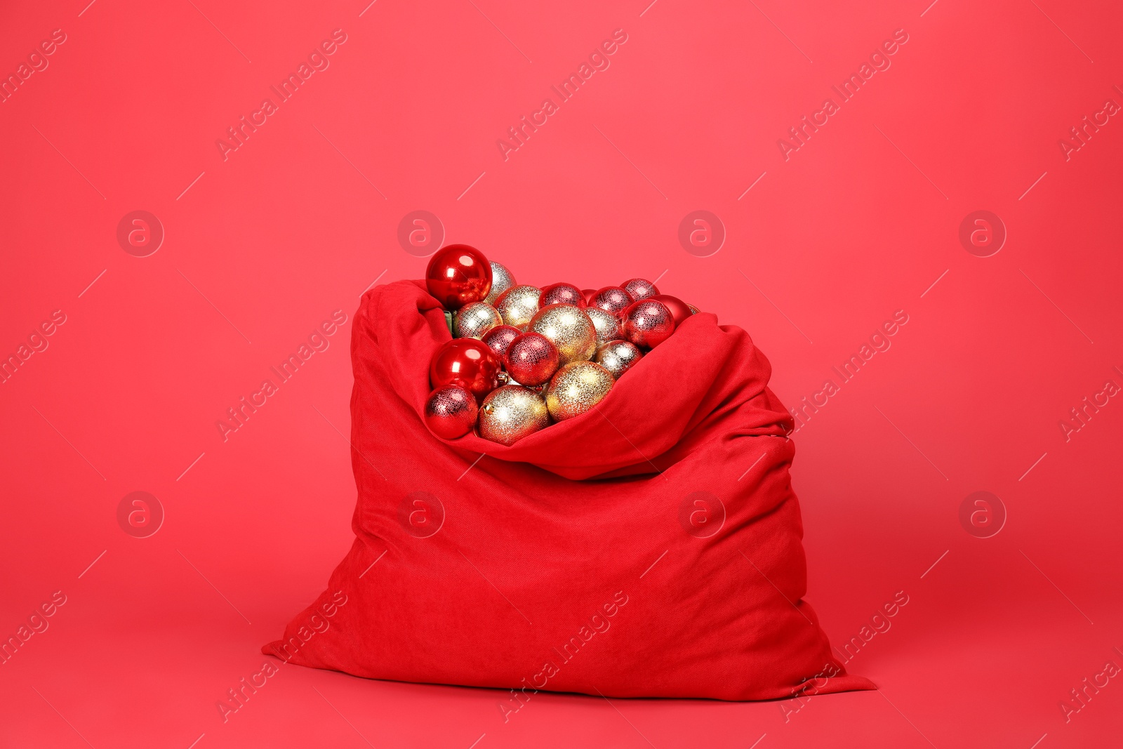 Photo of Santa Claus bag with baubles on red background