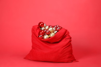 Photo of Santa Claus bag with baubles on red background