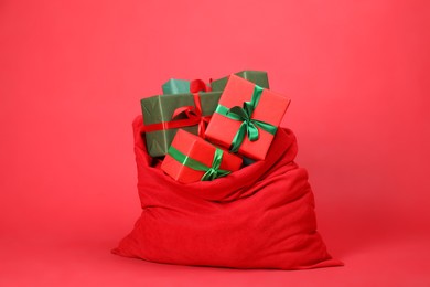 Photo of Santa Claus bag with gift boxes on red background