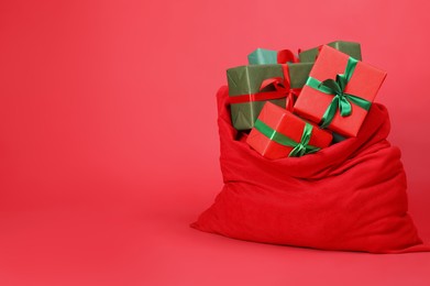 Photo of Santa Claus bag with gift boxes on red background, space for text