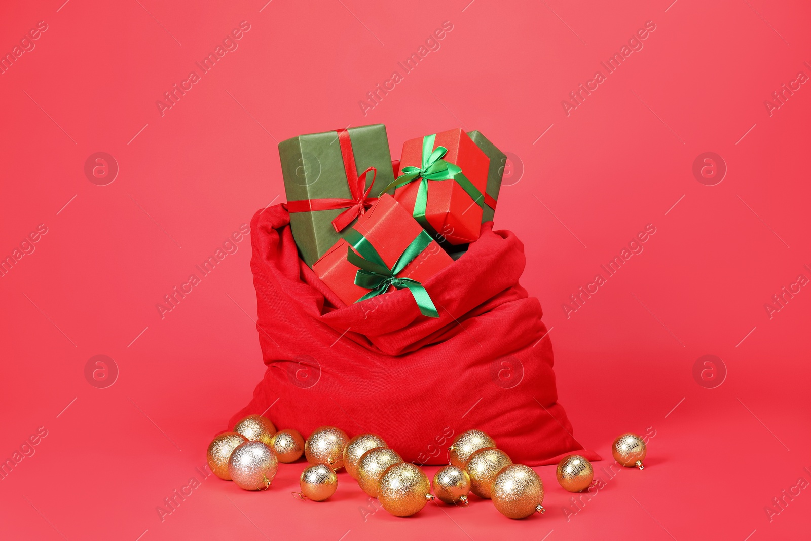 Photo of Santa Claus bag with baubles and gift boxes on red background