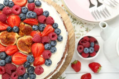 Photo of Delicious chocolate sponge cake with berries served on white wooden table, top view