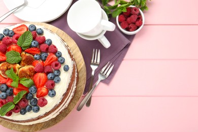 Delicious chocolate sponge cake with berries served on pink wooden table, top view. Space for text