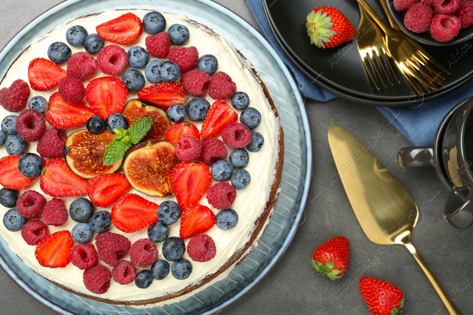 Photo of Delicious chocolate sponge cake with berries served on grey table, top view