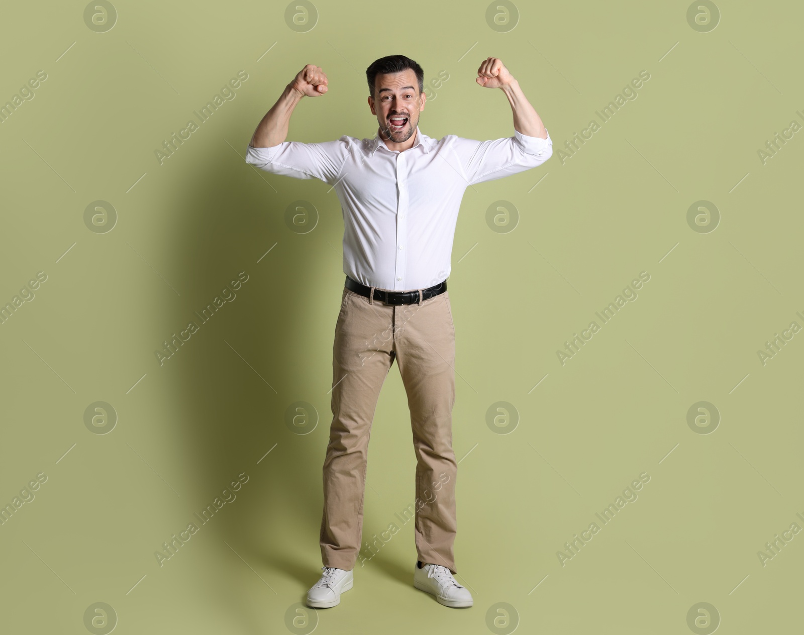 Photo of Portrait of happy winner on pale olive background