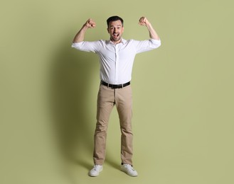 Portrait of happy winner on pale olive background