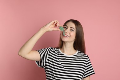 Photo of Young woman eating tasty gummy candy on pink background