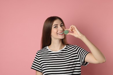 Photo of Young woman eating tasty gummy candy on pink background