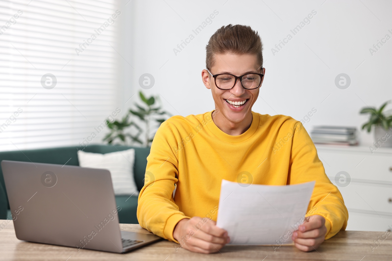 Photo of Happy student reading his good exam result at table indoors