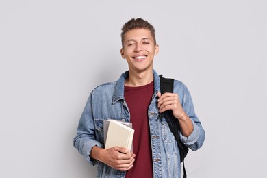 Photo of Happy student with backpack and books on grey background