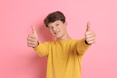 Photo of Happy teenage boy showing thumbs up on pink background