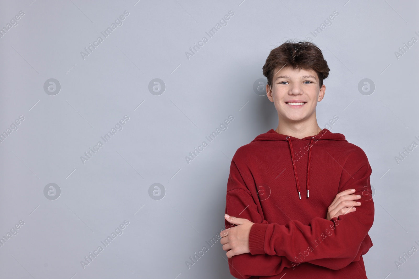 Photo of Portrait of happy teenage boy on light grey background, space for text