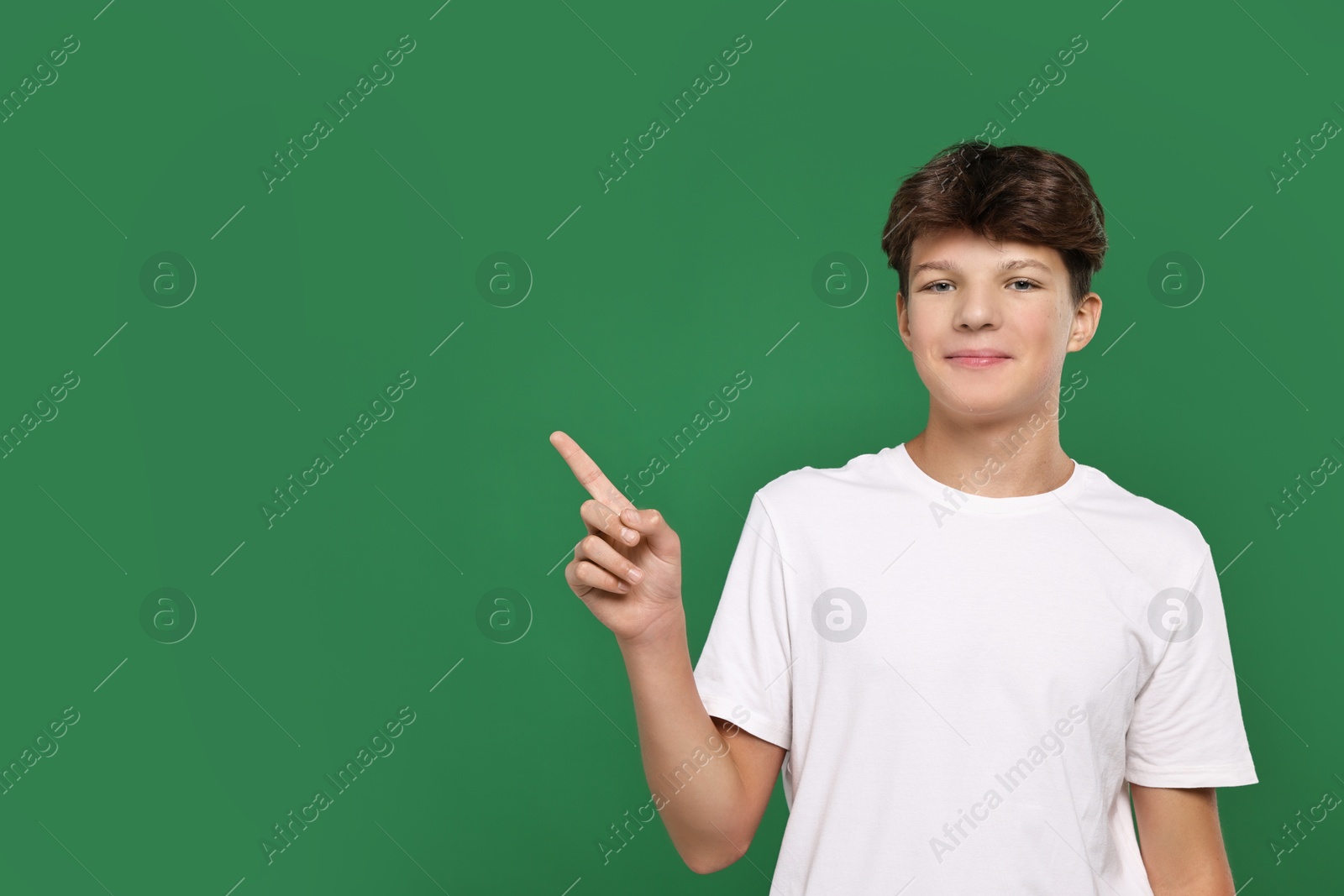 Photo of Portrait of teenage boy on green background, space for text