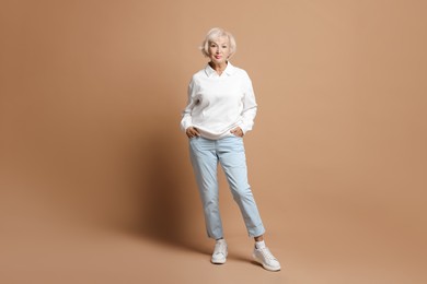 Photo of Full length portrait of beautiful senior woman on light brown background